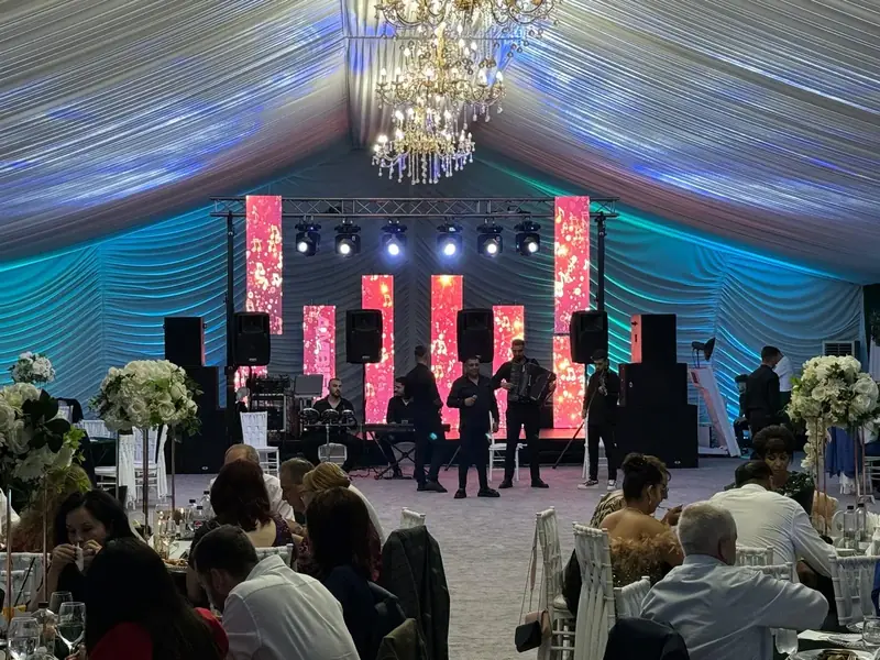 Formație live cântând pe scenă cu ecrane LED verticale, sistem PA și lumini ambientale la nuntă/eveniment