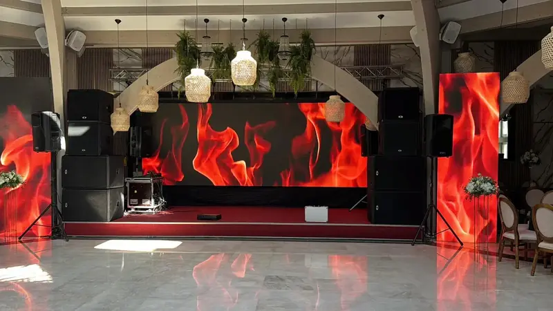 Scenă eveniment cu ecran LED central și ecrane verticale afișând vizualizări cu flăcări, plus sistem PA