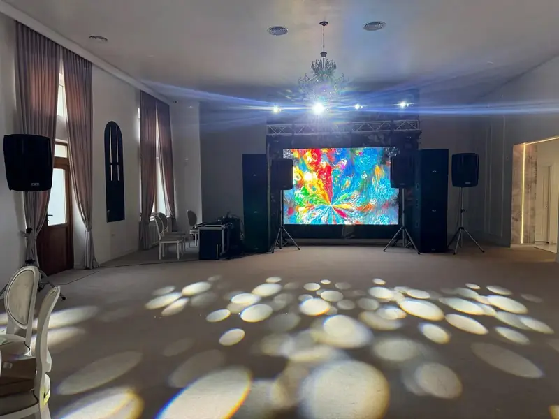 Scenă eveniment cu ecran LED afișând vizualizări colorate, sistem PA și efecte de lumini pe podea