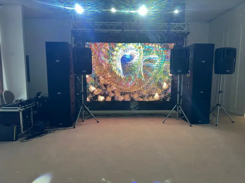Scenă eveniment cu ecran LED mare afișând vizualizări abstracte, sistem PA și schelă de lumini